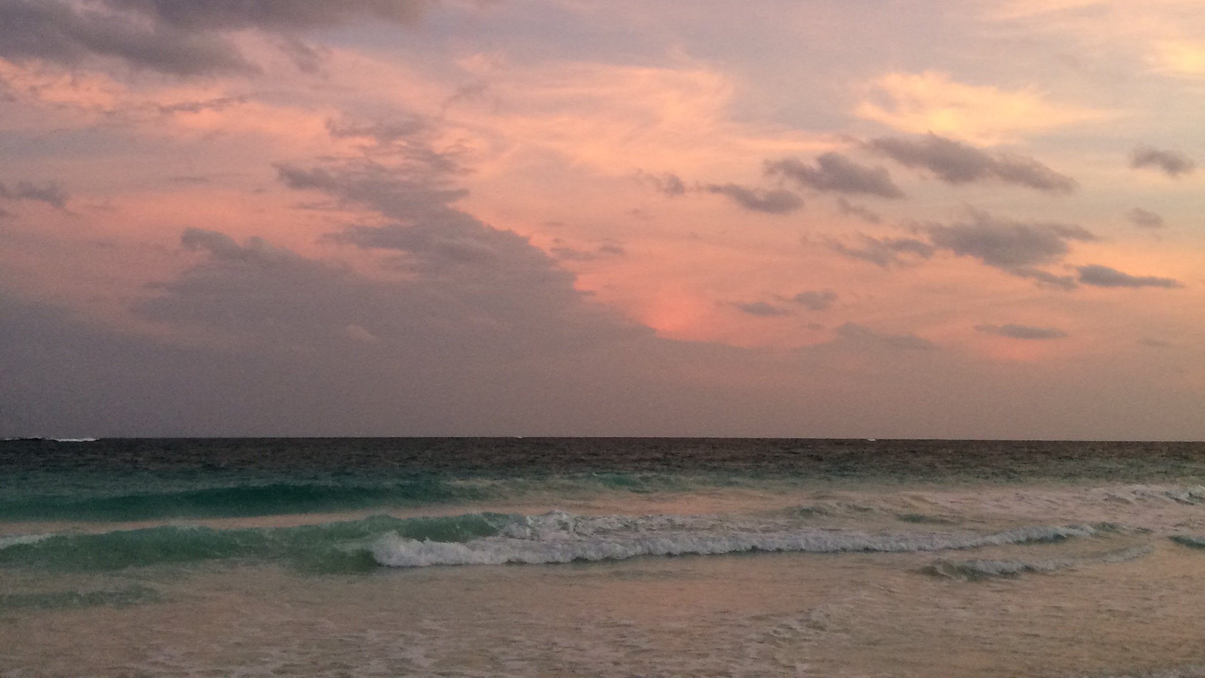 pink sunset with wispy clouds over turquoise waves